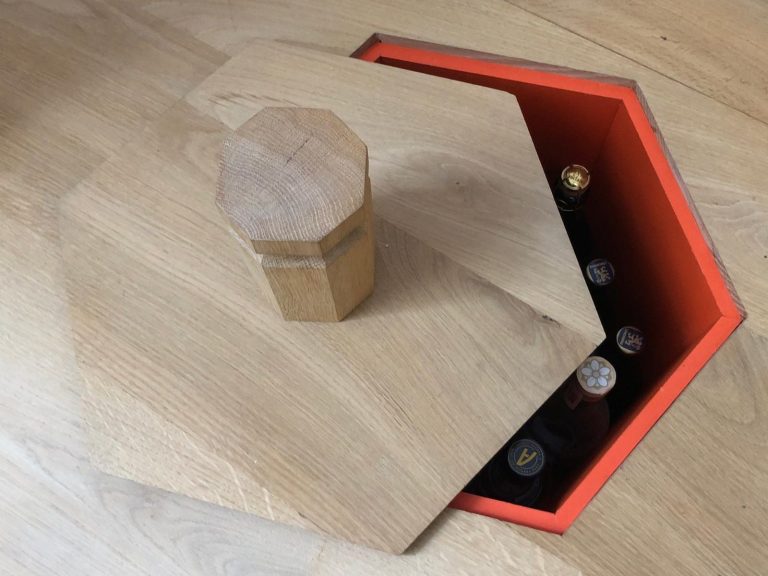 Kleinster Weinkeller der Welt Mini Weinkeller im Boden mit einem sechseckigen Deckel und orangem Innenraum, gefüllt mit Flaschen.